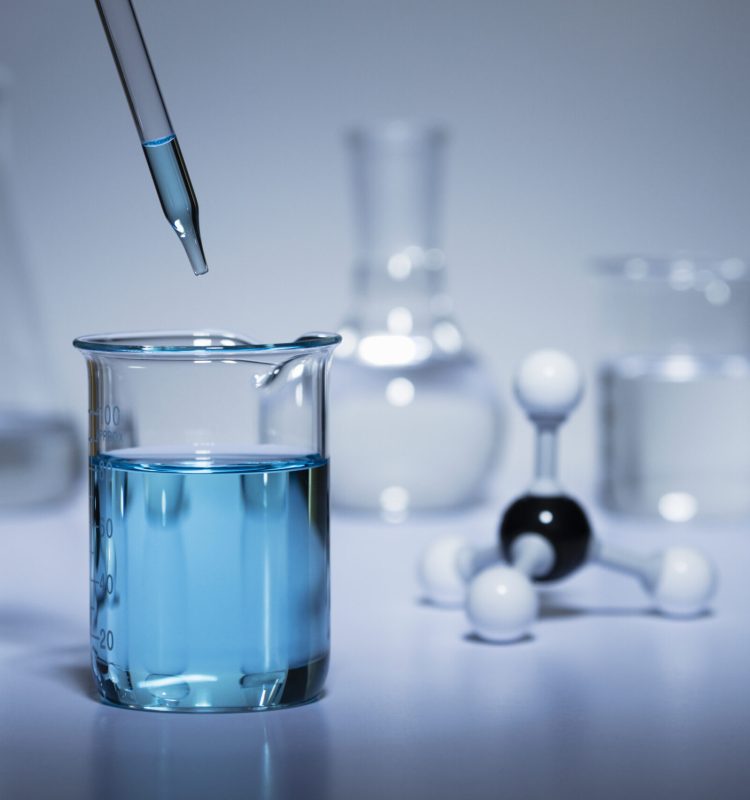 Chemistry research. A pipette transferring liquid to a beaker and a ball-and-stick molecular model